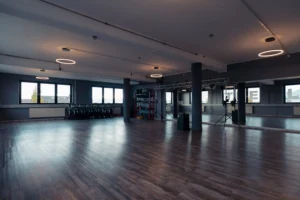 Großer Trainingsraum mit Holzboden und Panoramafenstern.