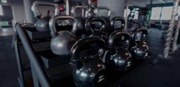 Schwarze Kettlebells in verschiedenen Gewichten auf einem Regal in einem modernen Fitnessstudio.