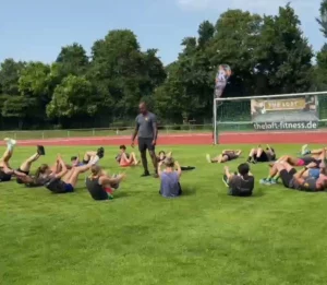 Outdoor-Bootcamp mit Trainer beim Hessentag 2025 – Teilnehmer:innen trainieren gemeinsam auf dem Rasen mit Core-Übungen
