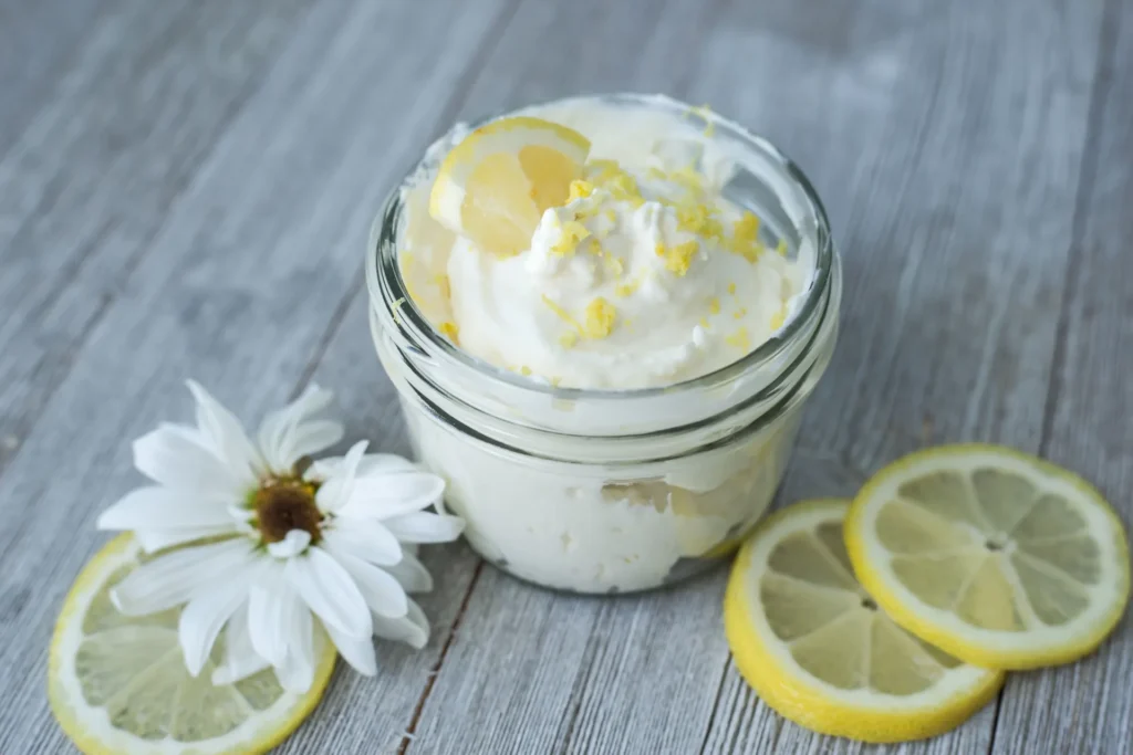 Frisches Zitronen-Protein-Dessert im Glas, garniert mit Zitronenzeste und Scheiben