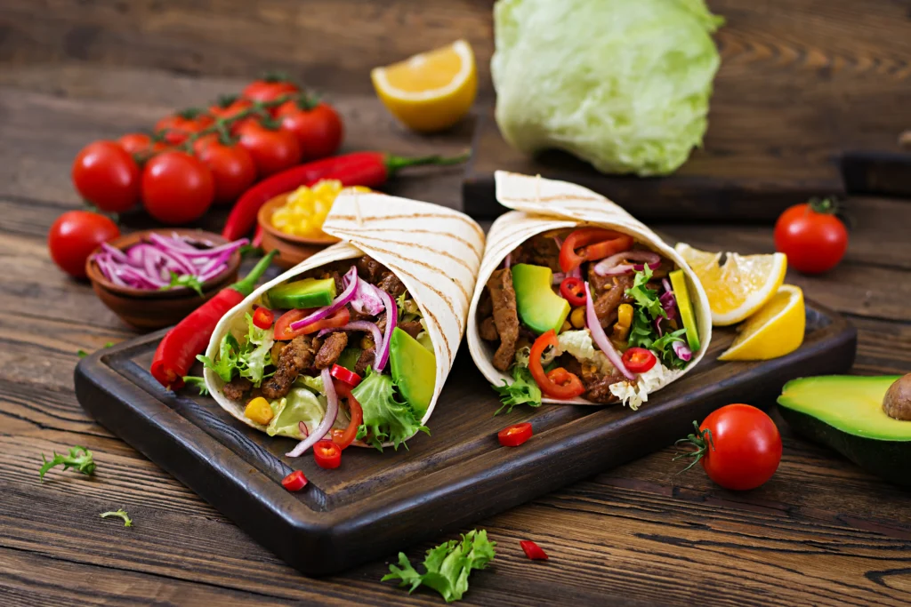Proteinreiche Beef Wraps mit Rindfleisch, schwarzen Bohnen, Reis und frischen Kräutern auf rustikalem Teller – ideale Mahlzeit für Muskelaufbau und sportliche Ernährung.