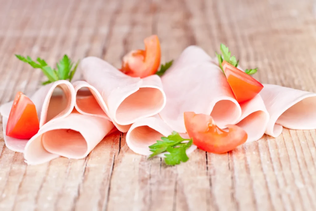 Putenaufschnitt mit Tomaten und Petersilie als eiweißreicher Snack für zwischendurch.
