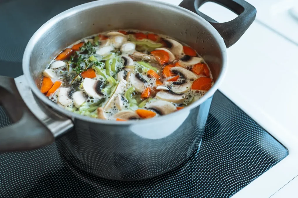 Frische Gemüsesuppe mit Champignons, Karotten und Kräutern in einem Kochtopf