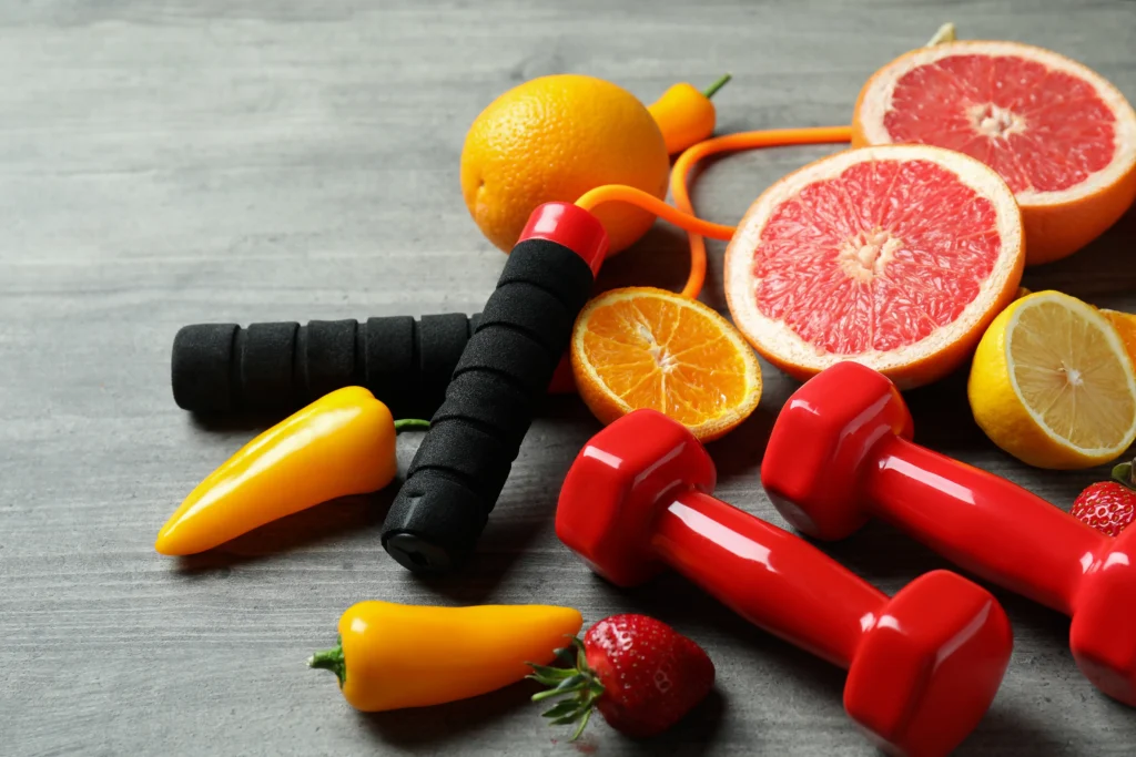 Rote Hanteln, Springseil und frisches Obst als Symbol für Fitness, Bewegung und gesunde Ernährung