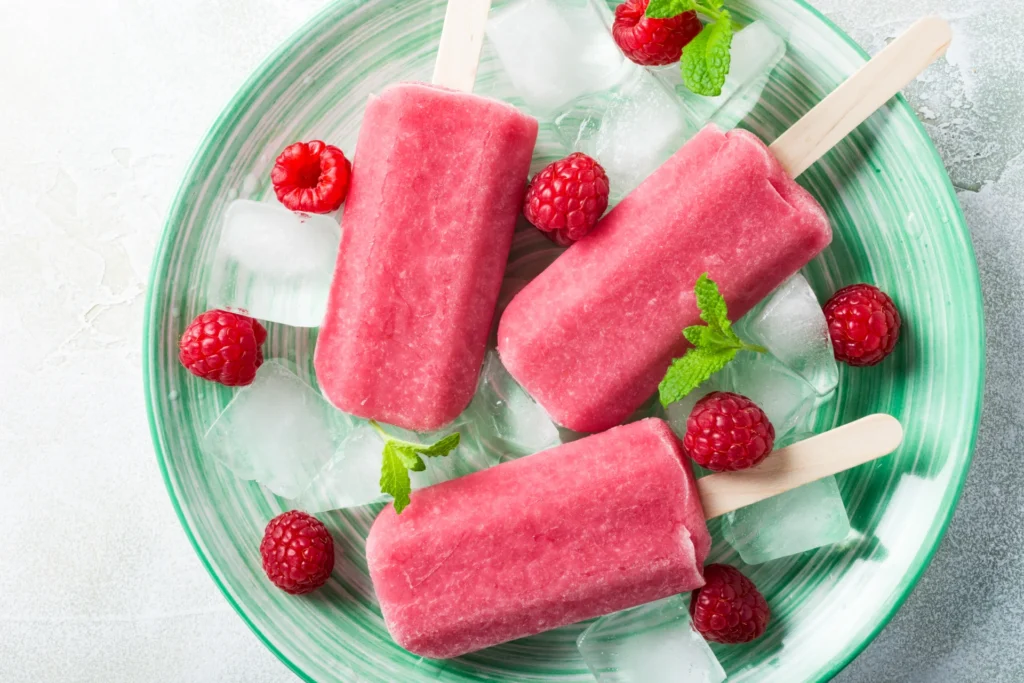 Selbst gemachtes Himbeer-Quarkeis am Stiel mit frischen Himbeeren und Minze
